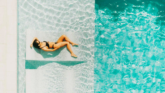 Donna sdraiata su una sedia a sdraio e in piscina