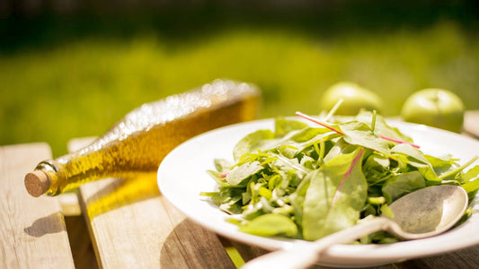 Piatto di insalata accompagnato da una bottiglia di olio d&#39;oliva