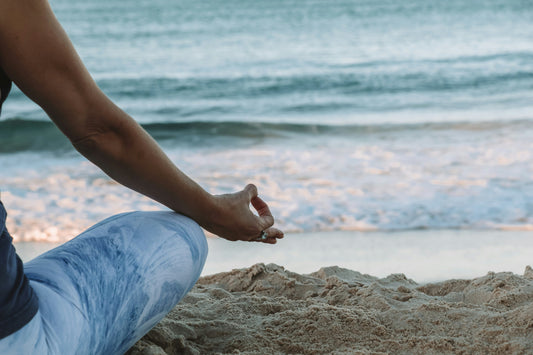 Donna in posizione yoga di fronte a una spiaggia 