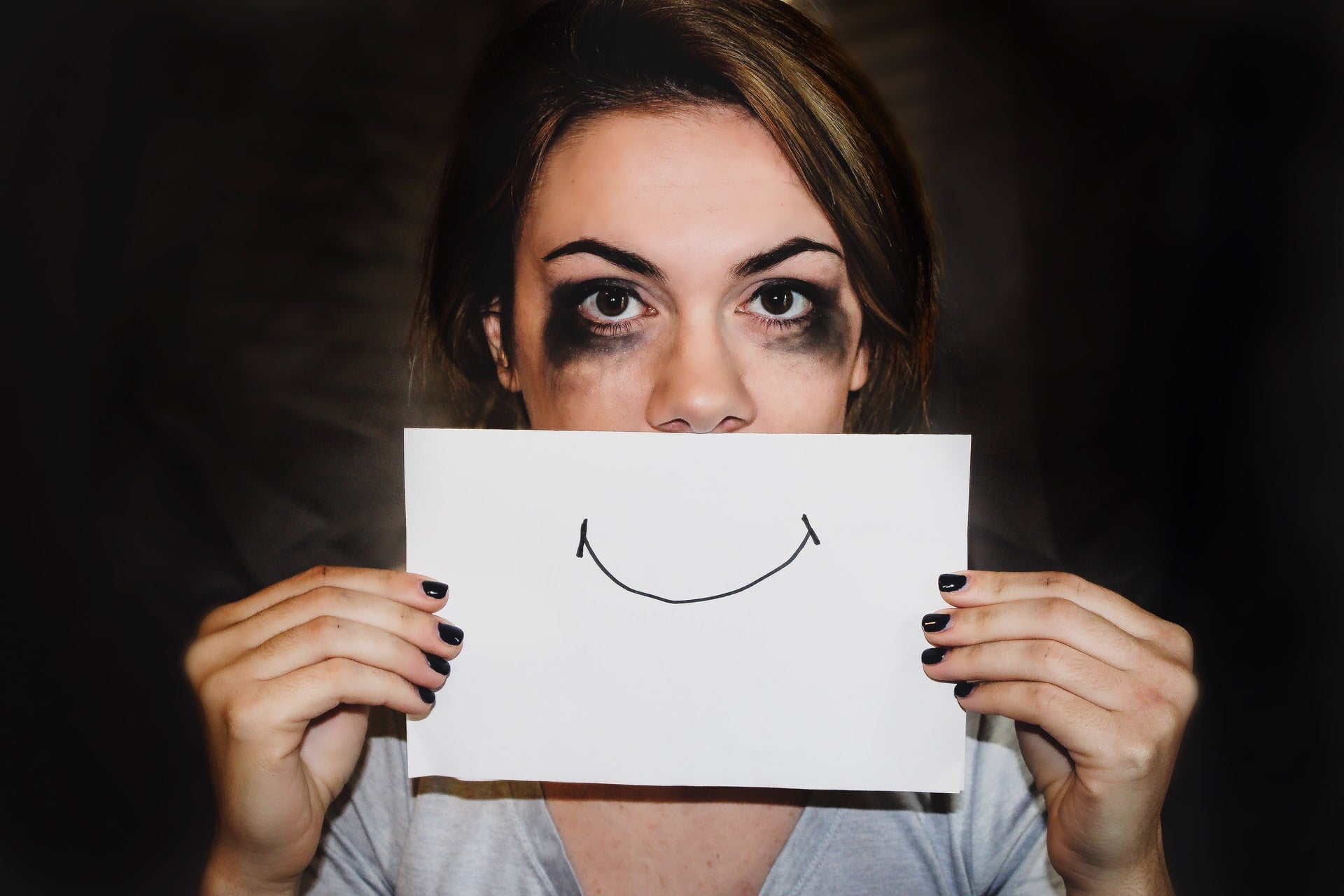 donna che piange con una faccina sorridente disegnata sulla bocca